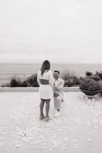 Luxury proposal photography shows emotional moment as Jeremy drops to one knee during San Clemente beach house proposal